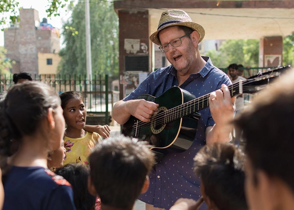 Man med gitarr spelar för barn
